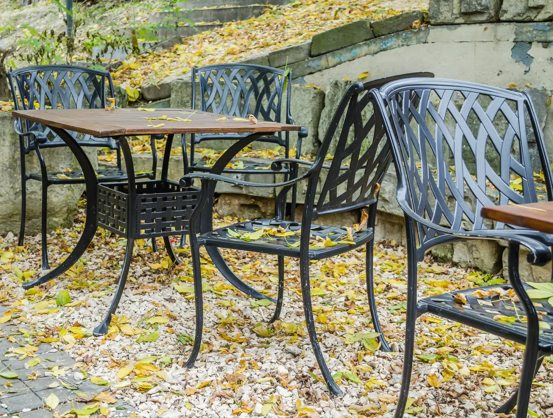 Garde-corps terrasse en fer forgé noir et mur en pierre Terrasse avec garde-corps en fer noir, carrelage effet bois et mur en pierre naturelle sur fond de forêt.